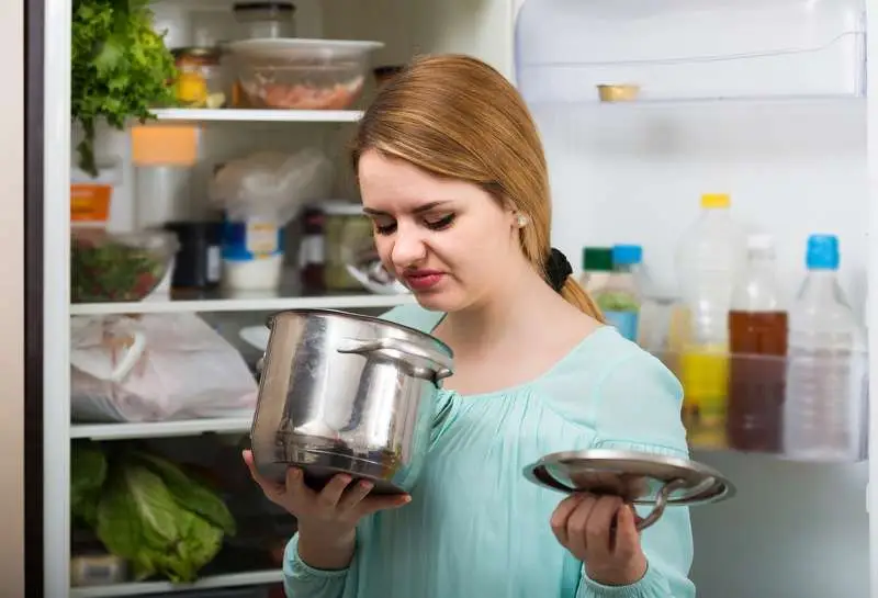 Woman smelling pot from refrigerator